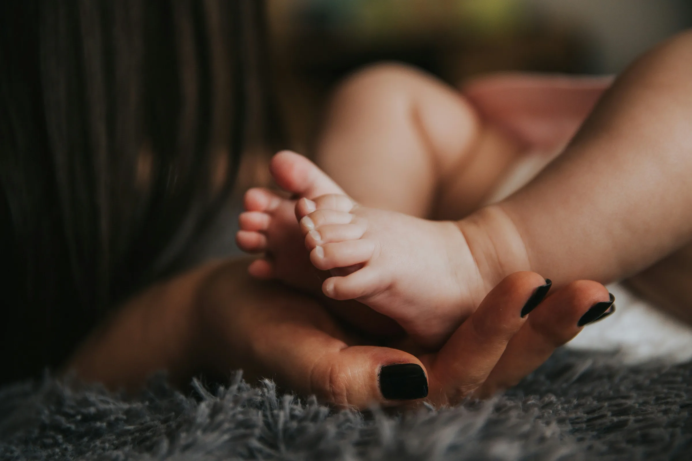 baby’s feet supported by adult hands