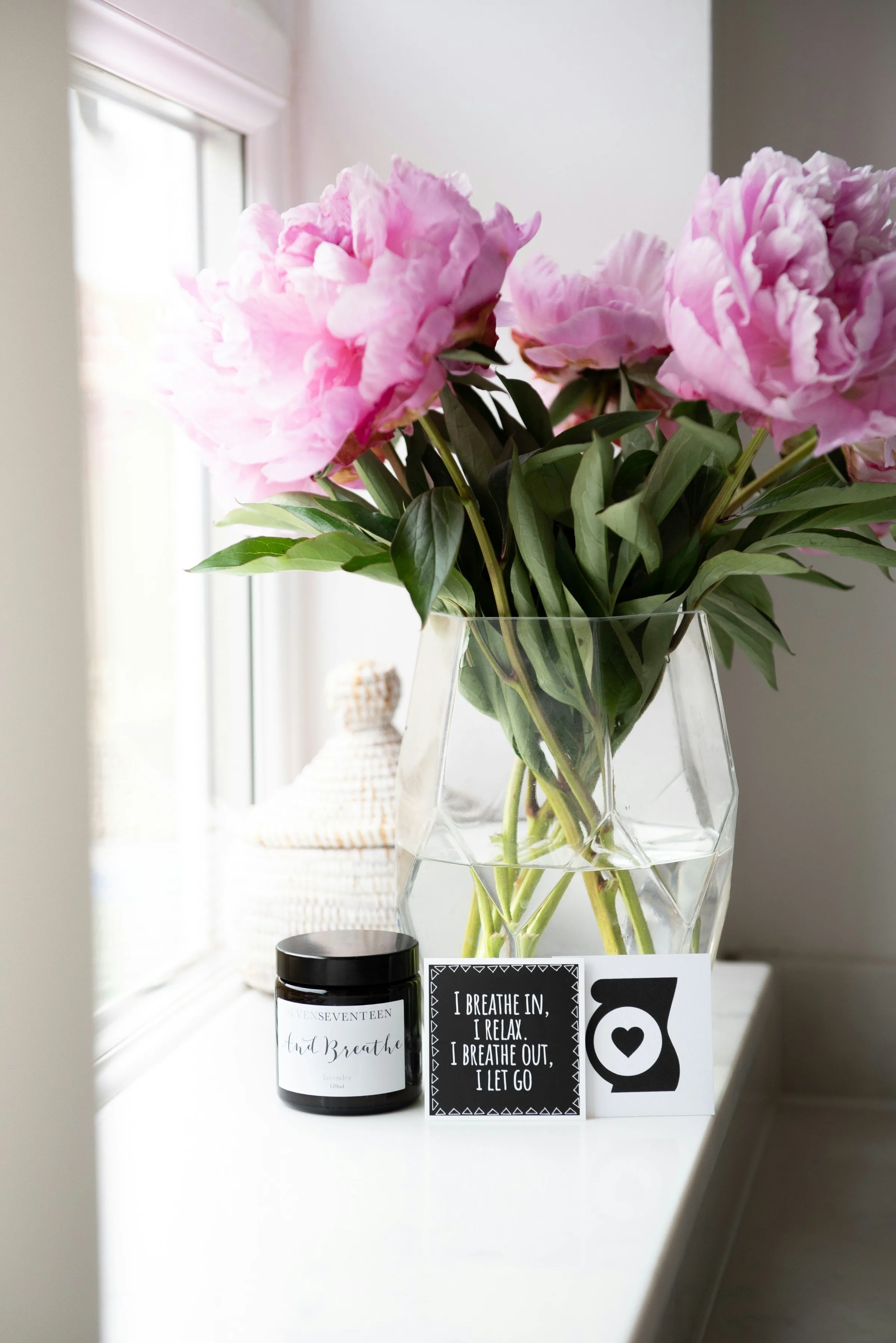 Flowers arranged beside a candle and a positive affirmation