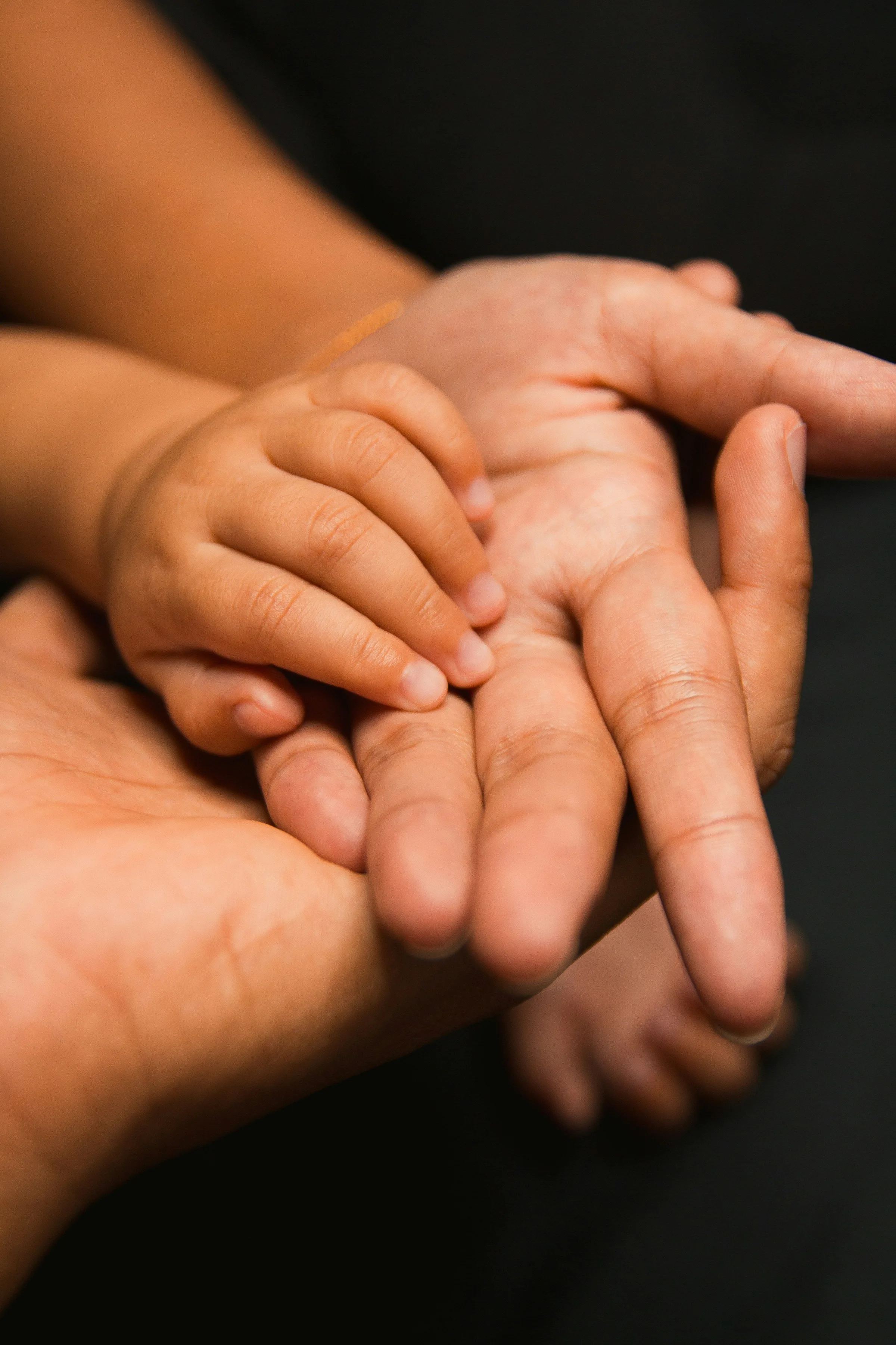 parents hands holding baby's hand gently palm to palm